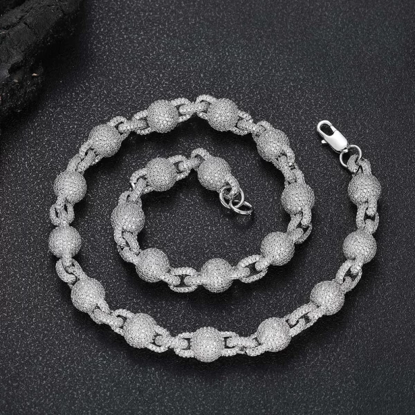 Elevate your look with the Iced Beaded Rolo Chain in White Gold. This 11mm chain features an intricate beaded design, set with VVS Simulated Diamonds for maximum brilliance. The White Gold finish brings a sleek and sophisticated touch, perfect for both casual and formal occasions. Whether worn alone or layered with other chains, this piece adds a modern twist to your style while offering durability and shine.