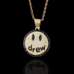 Show off your playful side with this Iced Smile Drew Emoji Pendant in Yellow Gold. Inspired by modern pop culture, this pendant captures the essence of fun and style with a detailed smiley face design. Gold-plated and encrusted with stones for extra sparkle, it’s a great accessory for those who love to make a statement. Hypoallergenic, waterproof, and scratch-resistant, it’s perfect for daily wear. This pendant is ideal for anyone looking to add a pop of personality to their jewelry collection with a Hip Hop influence.