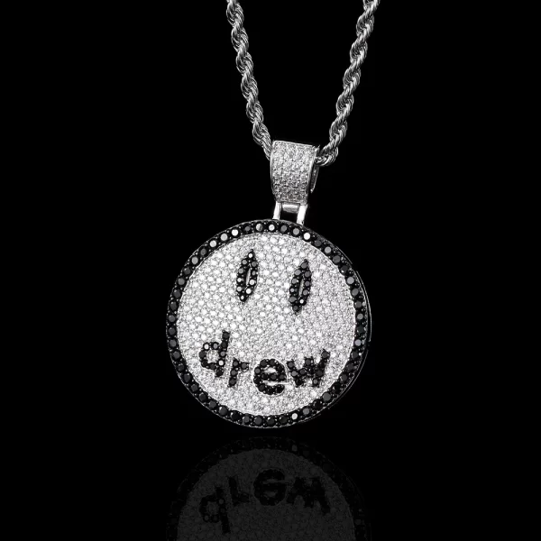 The Iced Smile Drew Emoji Pendant in White Gold offers a sleek and vibrant twist on the classic smiley face. Covered in sparkling stones, the white gold-plated design shines from every angle, making it a standout piece in any collection. Hypoallergenic and waterproof, it’s ideal for those who want to combine fun and Hip Hop style.